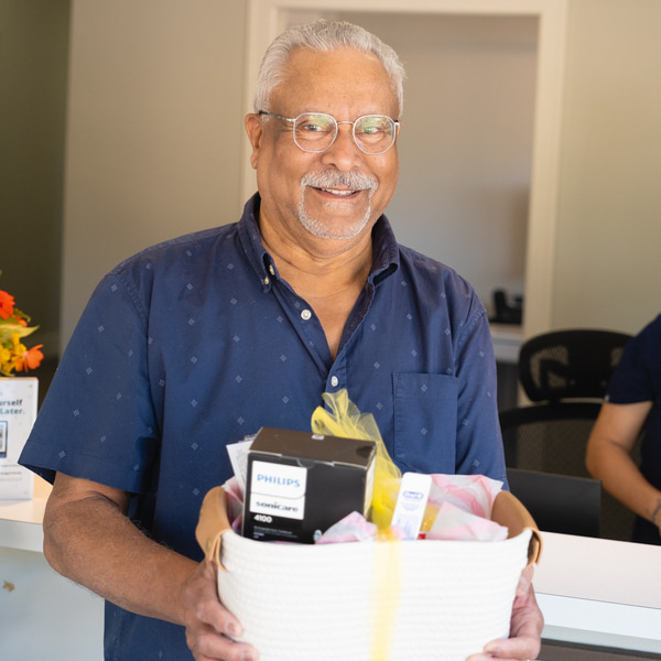 A delighted patient receives a complimentary gift basket from the Hylan Dental Care family
