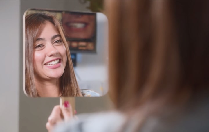 A woman gazes into the mirror, joyfully smiling