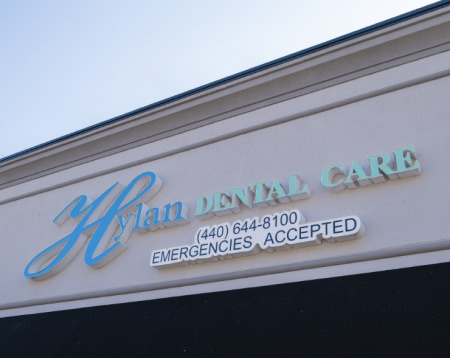 The main entrance of Hylan Dental Care adorned with the company logo and contact details