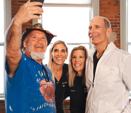 The Hylan Dental Care team is capturing a joyful moment with their patient, taking a selfie and sharing smiles