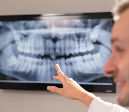 The dentist is indicating specific details on a digital x-ray scan