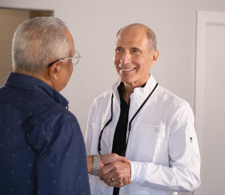 Dr. Hylan is shaking hands with his patient and smiling