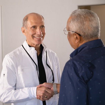 Dr Hylan shaking hand with his happy patient