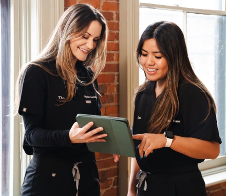 Two woman are looking at tablet and smiling