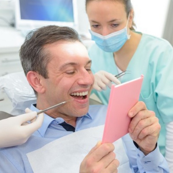 Happy man in a dental chair with his doctors